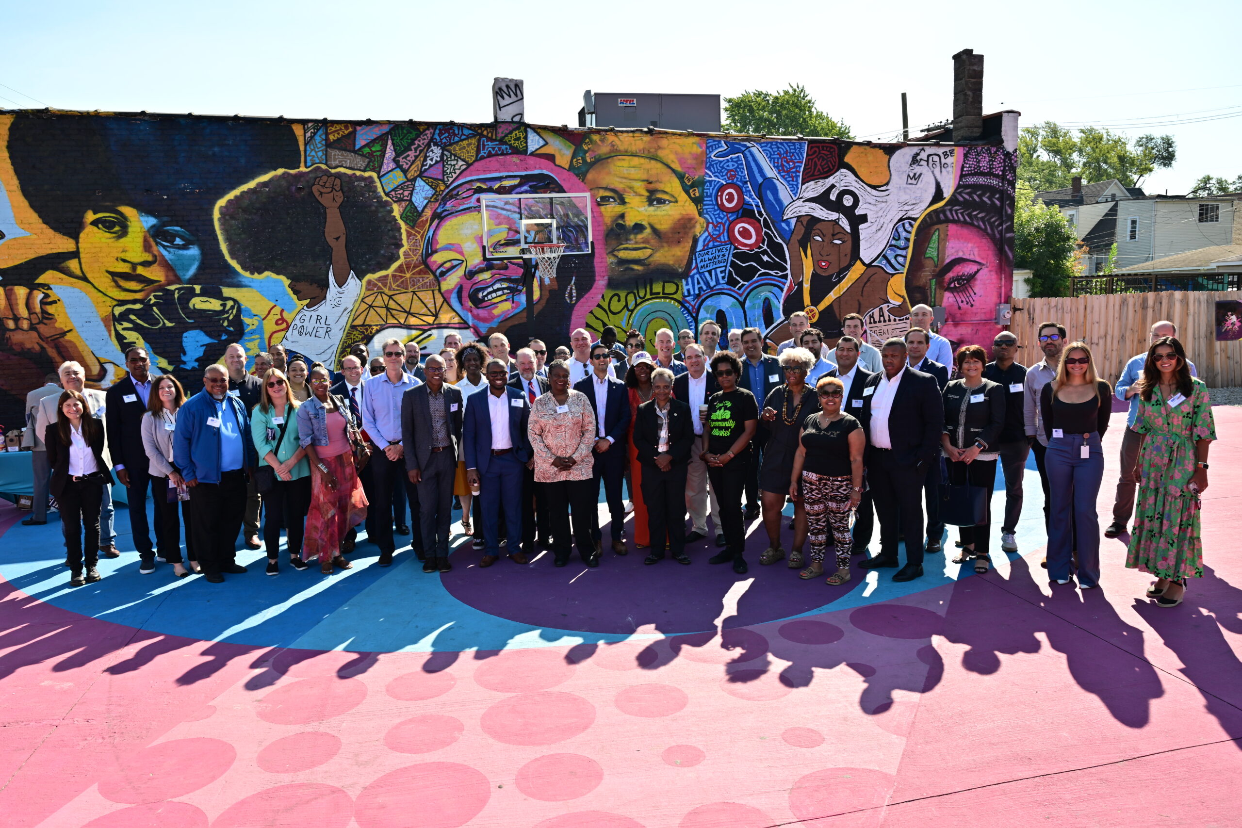colorful mural of collage African American people with a group standing in front for a photo