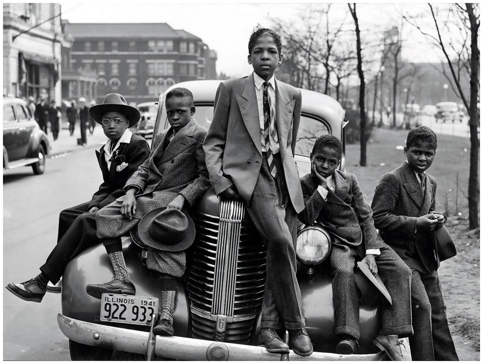black man and boys sit on a car